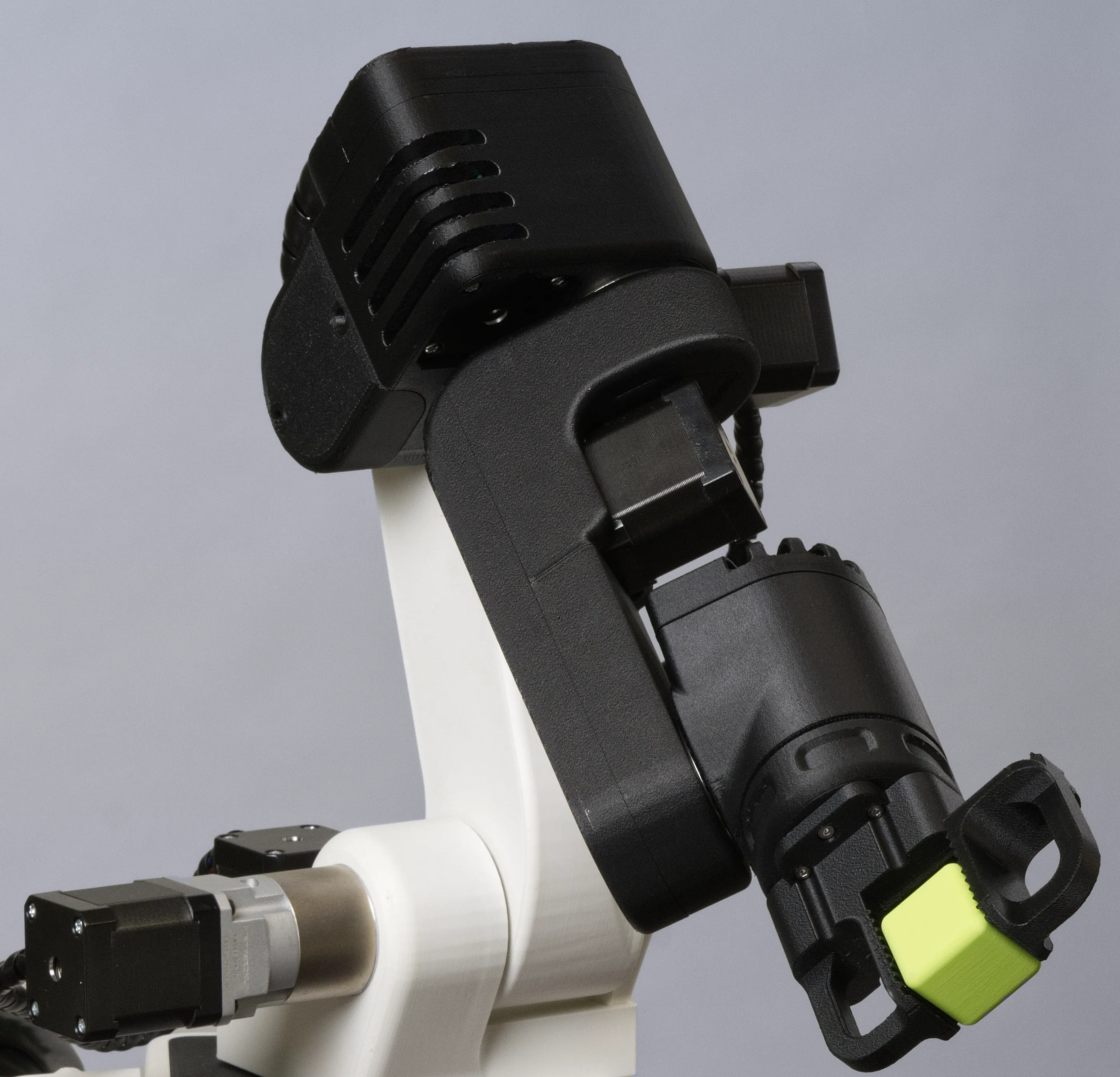 A photo of the 3D-printed robot GK-RA with gripper and a plastic cube moving to the right.